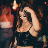 Young woman in a black crop top smiling and enjoying a lively party atmosphere, surrounded by friends, reflecting the fun and energy of events like bachelorette parties and celebrations.
